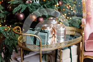 Golden cart with present gift boxes near Christmas tree decorated with handmade eco paper balls