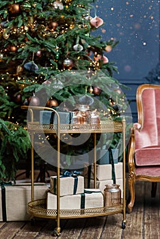 Golden cart with present gift boxes near Christmas tree decorated with handmade eco paper balls