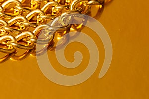 Golden chain. Detail of a yellow iron chain. Metal chain link on the gold background. Decorative jewelry. Luxury design brilliant