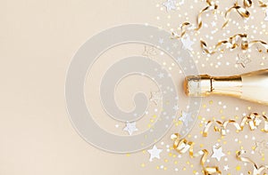 Golden champagne bottle with confetti stars and party streamers top view. Christmas, birthday or wedding background. Flat lay