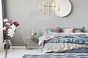 Golden chandelier above king size bed with blue, beige and pastel pink sheets photo