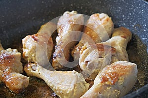 Golden chicken legs in batter fried in a pan