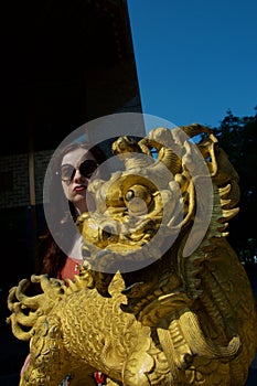 Golden Chinese Dragon Statue with young white female tourist pouting