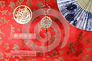 Golden chinese tiger symbol, chinese bamboo paper fan and fortune hunger from lucky coins on red fabric with birds and dragons.