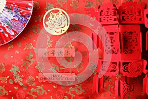 Golden chinese tiger symbol, chinese bamboo paper fan and red chinese lantern on red fabric with traditional chinese ornament of