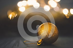 Golden christmas ball on holiday lights background. New year greeting card. Copy space for text
