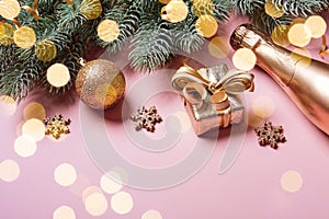 Golden christmas decor and bauble on pink background, spruce branches and golden bokeh lights