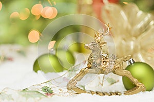 Golden Christmas Reindeer Ornament Among Snow, Bulbs and Ribbon