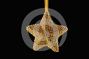 Golden Christmas star ornament on ribbon isolated on black background