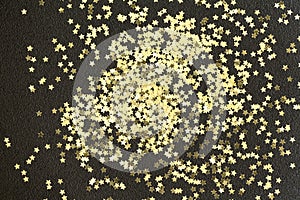 Golden Christmas stars on black background. Golden glitter texture abstract background.