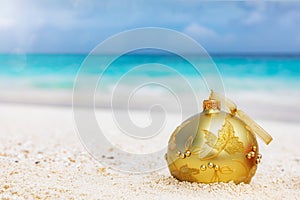 Golden christmas tree ball on a tropical beach