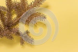 Golden Christmas tree branch on yellow backgound