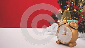 Golden clock decorated in Christmas celebration theme on white table reb background with copy-space, family spent time together in