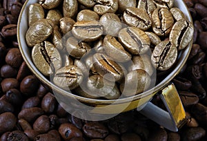 Golden coffee beans in a cup. Golden coffee as a symbol of quality and luxury. The concept of luxury and originality. close up