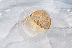 Golden coin with bitcoin symbol frozen in ice