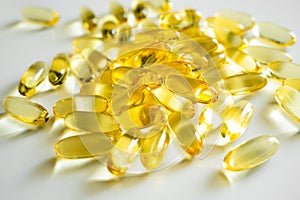 Golden color fish oil supplement in soft gel capsule on white background. Healthy vitamins, omega 3. Oil filled capsules