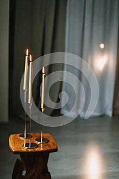 Golden color painted long candles on wooden table at home. Modern living room interior composition with Christmas