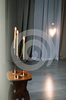 Golden color painted long candles on wooden table at home. Modern living room interior composition with Christmas