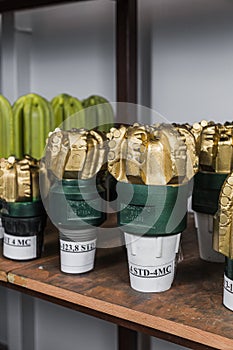 Golden color rock Drill Bits on shelving in stock. Oil drilling equipment for drilling rig operation on oil platform in