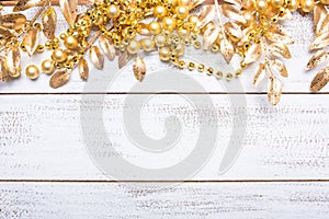 Golden colored Christmas decorations on a white wood background with copy space. Leaves, garland, berries etc.