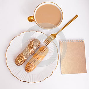 Golden colored eclairs on plate, knife and fork, cup of coffee