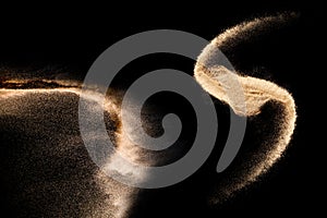 Golden colored sand splash against dark background.