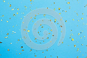 Golden confetti on blue paper background. Festive holiday backdrop. Birthday congratulations Christmas New Year.