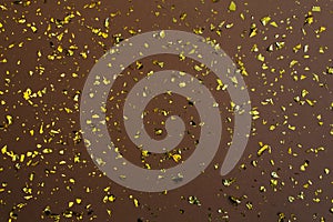 Golden confetti on brown earthen paper background. Festive holiday backdrop. Birthday congratulations Christmas New Year.