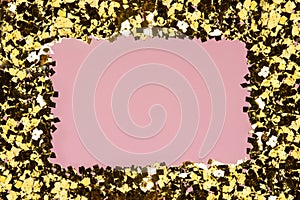 Golden confetti glitter frame on pink background. Festive holiday pastel backdrop. Greeteng cards template. Flat style