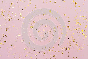 Golden confetti on pastel pink paper background. Festive holiday backdrop. Birthday congratulations Christmas New Year. Valentines