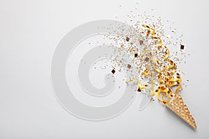 Golden confetti and streamers with party cracker on white background, top view. Space for text
