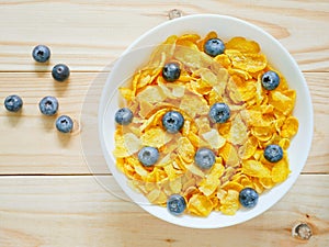 Golden cornflakes cereal with blueberries on wooden background