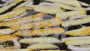 Golden crispy wedges of potatoes and onions are fried in oil in a hot skillet in the kitchen. Sprinkle the seasoning