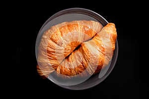 Golden croissants on a black background, top view. Fresh butter croissants