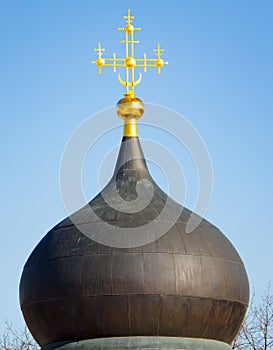 The golden cross on the Orthodox Temple against the blue sky