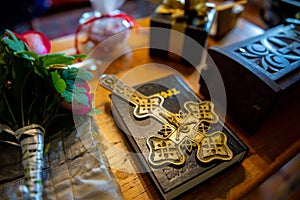 A golden cross on the table on top of a bible in a church, preparing for a baptism ritual.