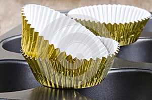 Golden cup cake cases on a baking tin