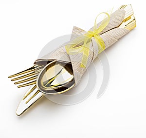 Golden cutlery knife, fork and spoon with napkin and bow. Ready for picnic. Isolated on white background