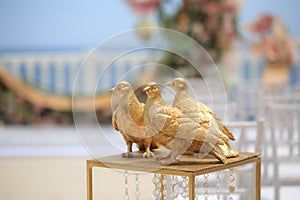 Golden decorative doves on the background of the wedding ceremony.