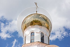 A golden dome with a cross shines in the sun.