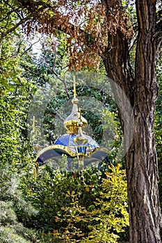 Golden domes of Christian chapel surrounded by green trees