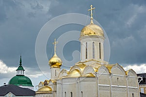 Golden Domes of Trinity Cathedral Against Dark Rain Clouds