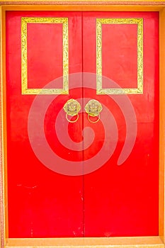 Golden door knocker in the shape of lion with ring on a red wooden door. Close up wooden Chinese style red door with lion head