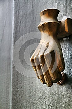 Golden doorknocker with hand shape on old green wooden door