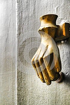 Golden doorknocker with hand shape on old green wooden door