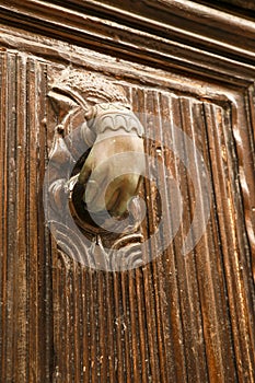 Golden doorknocker with hand shape on old wooden door