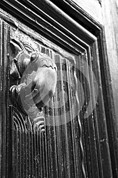 Golden doorknocker with hand shape on old wooden door