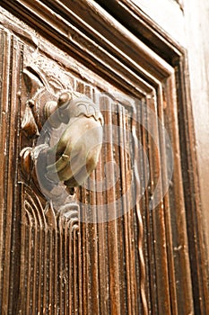 Golden doorknocker with hand shape on old wooden door
