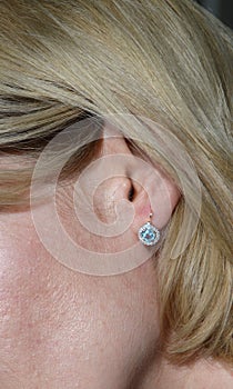 Golden earring with blue topaz and few diamonds in model`s ear