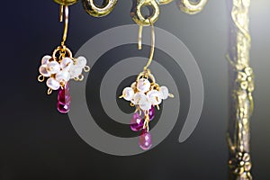 Golden earrings with red rubies with white pearls on black background.